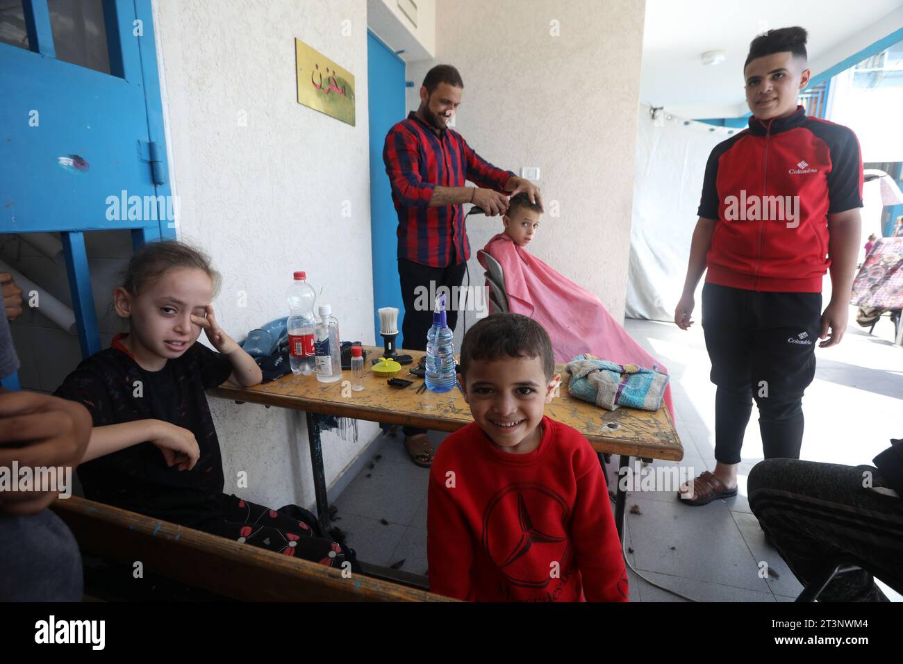 Rafah, Gaza. 25 octobre 2023. Un coiffeur coupe les cheveux d’un enfant, fuyant avec sa famille