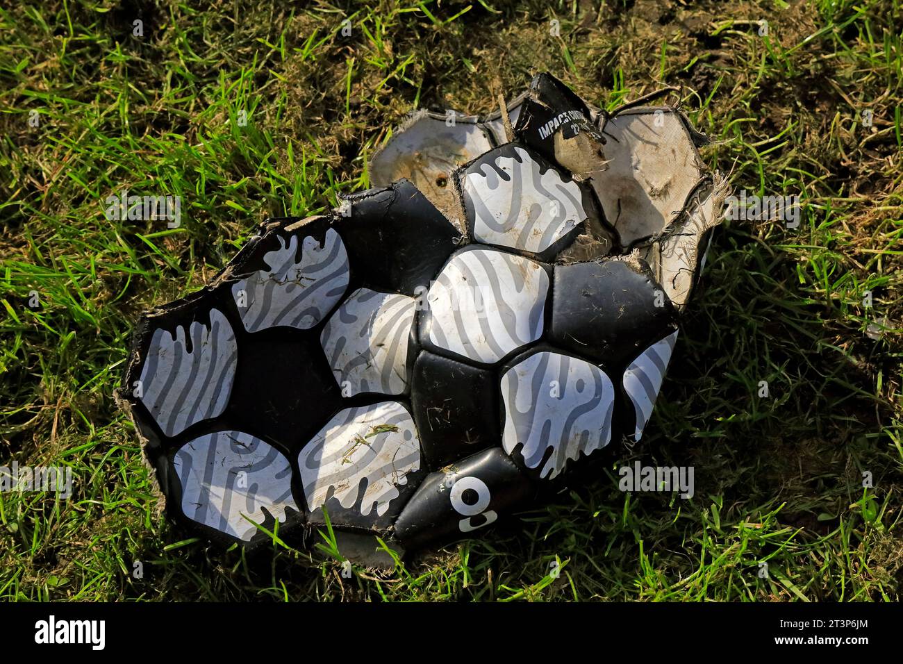 Football déchiré, cassé, abandonné laissé sur l'herbe. Objet trouvé. Cardiff. Prise à l'automne 2023. Octobre Banque D'Images