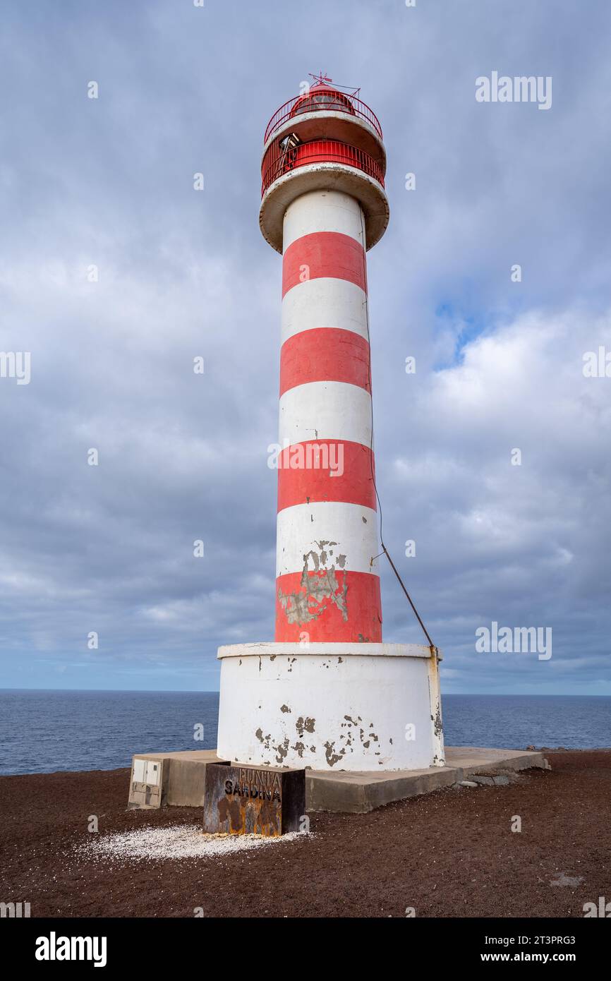 Vue à faible angle du phare de Punta Sardina, sur l'île de Gran Canaria, Espagne. Peint en bandes horizontales rouges et blanches avec ciel nuageux et mer dedans Banque D'Images