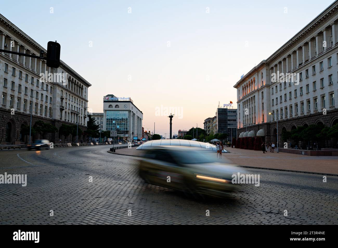 Voitures rapides en Bulgarie. La statue de Sofia s'élève majestueusement en arrière-plan, tandis que les lucarnes du complexe serdika scintillent devant. Banque D'Images