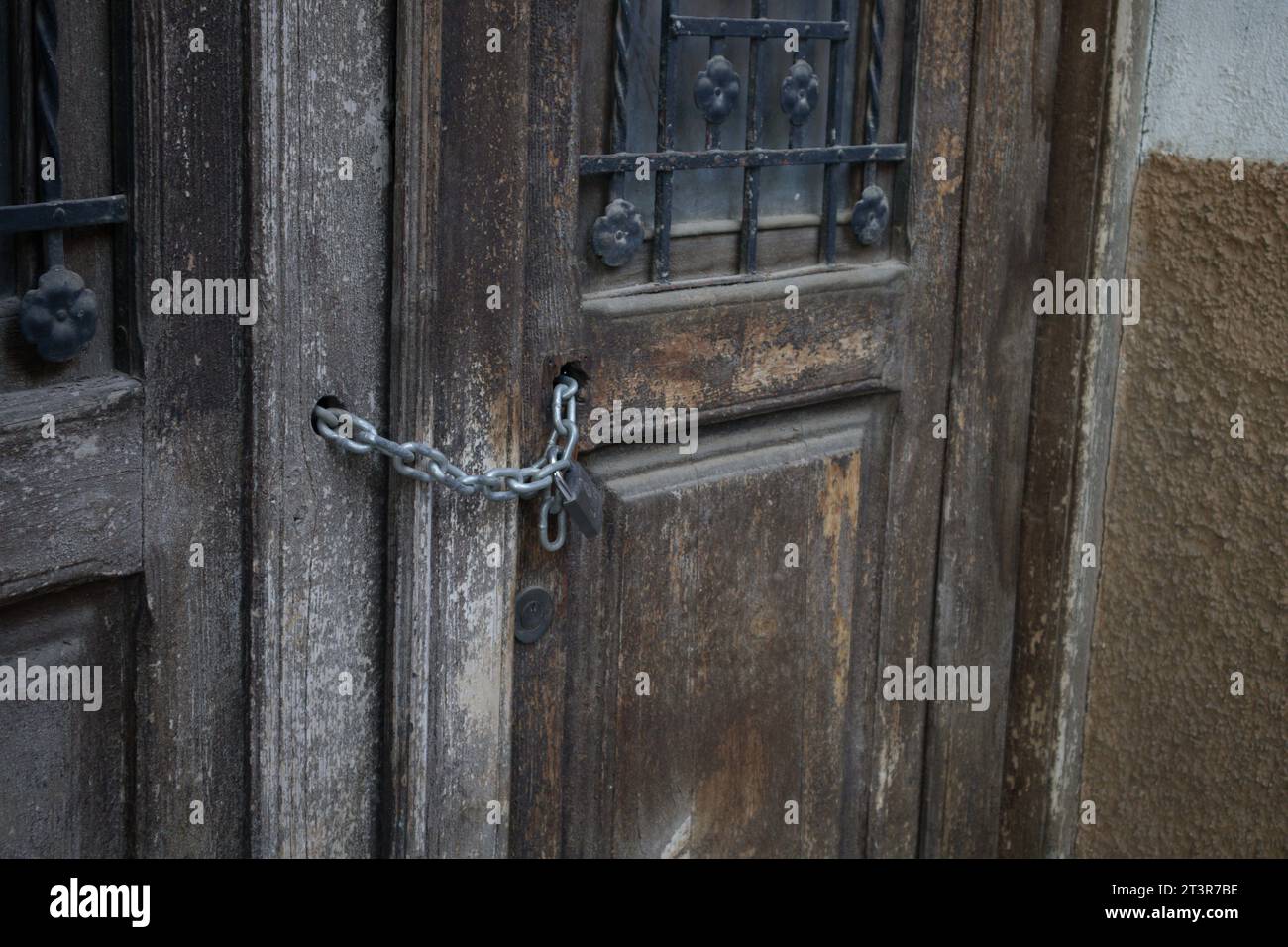Gros plan d'une porte en bois d'une vieille maison fermée avec un cadenas et une chaîne pour empêcher les squatters d'entrer Banque D'Images