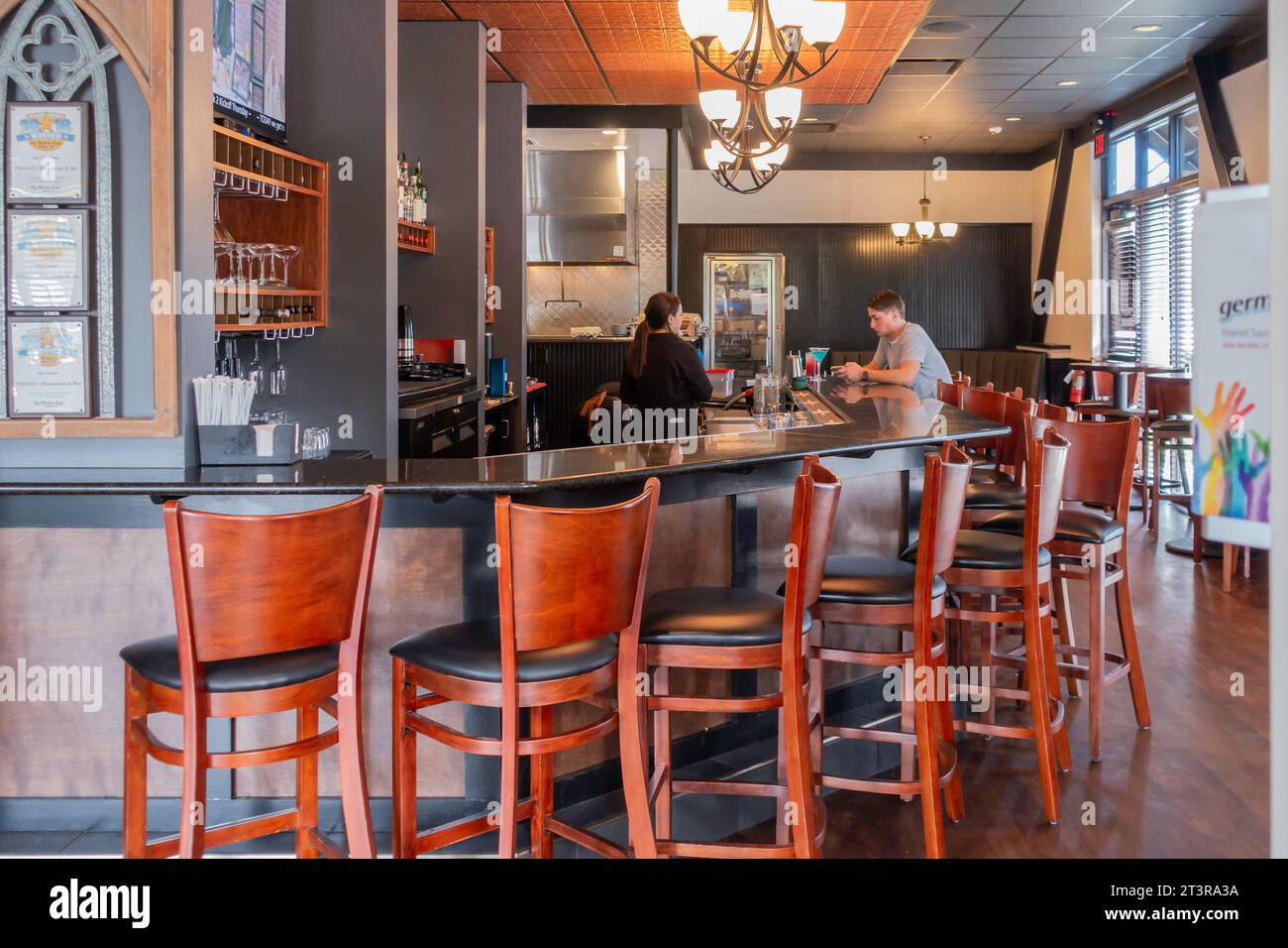 Douze restaurants et bars dans un espace bar intérieur avec un client masculin avec sa boisson adulte et une serveuse. Wichita, Kansas, États-Unis. Banque D'Images