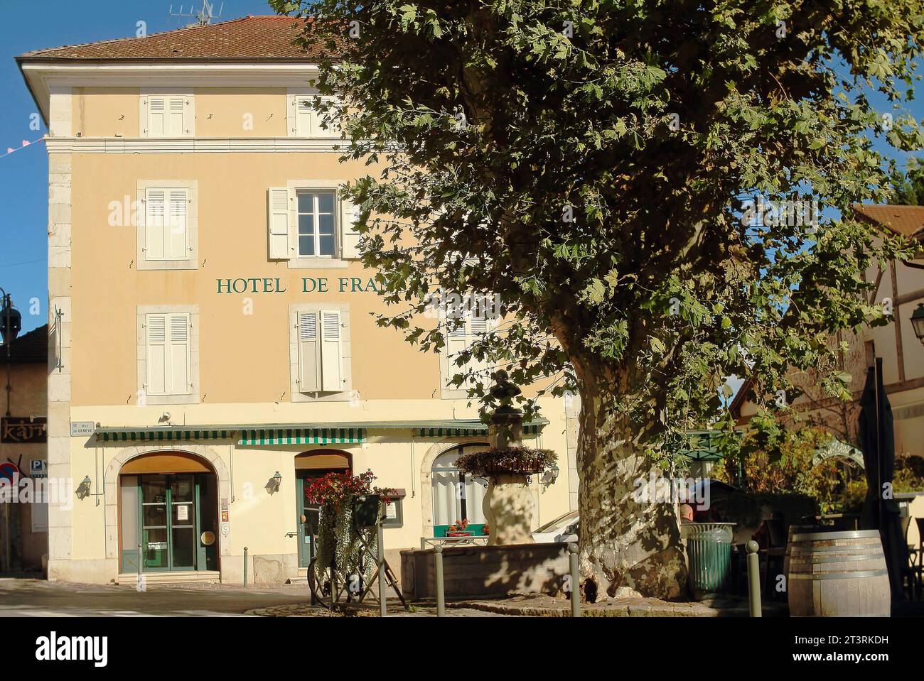 Vue de l'Hôtel France avec une belle fontaine antique et grand arbre vieux à Ferney-Voltaire, France. Ferney-Voltaire une ville et commune à Fran Banque D'Images