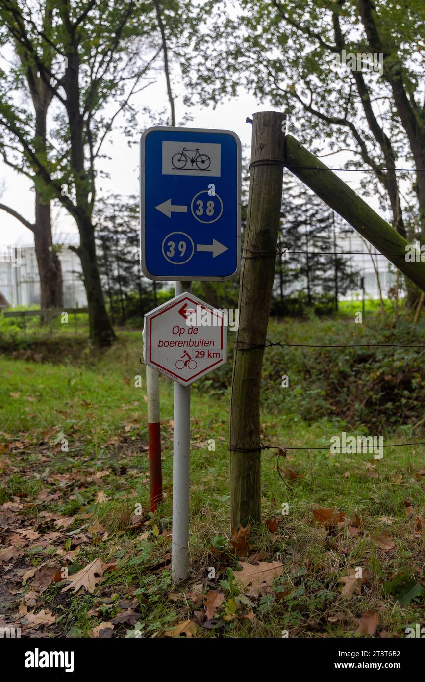 Panneaux avec des directions de piste cyclable du réseau cyclable belge sur la piste cyclable rurale 'Op de boerenbuitn' le long des fermes, des champs, etc Banque D'Images