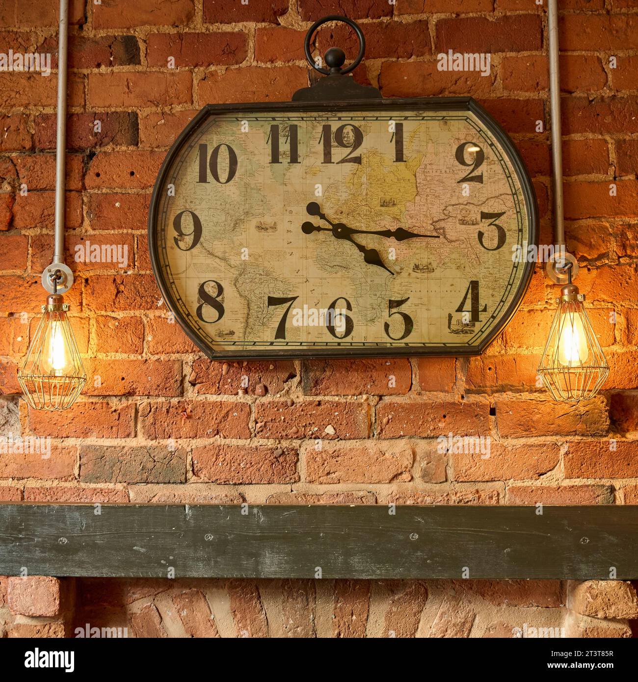 Grande horloge carrée sur le mur de briques au-dessus de la cheminée en bois Banque D'Images
