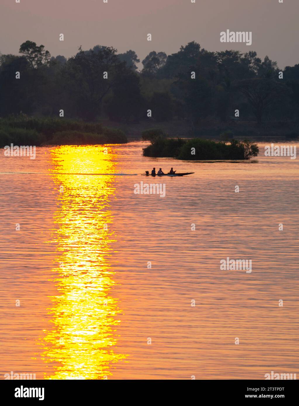 Silhouettes de figures humaines dans un petit canoë,dérivant à travers les eaux calmes et paisibles du Mékong,à travers des rayons de lumière dorée réfléchis sur le wat Banque D'Images