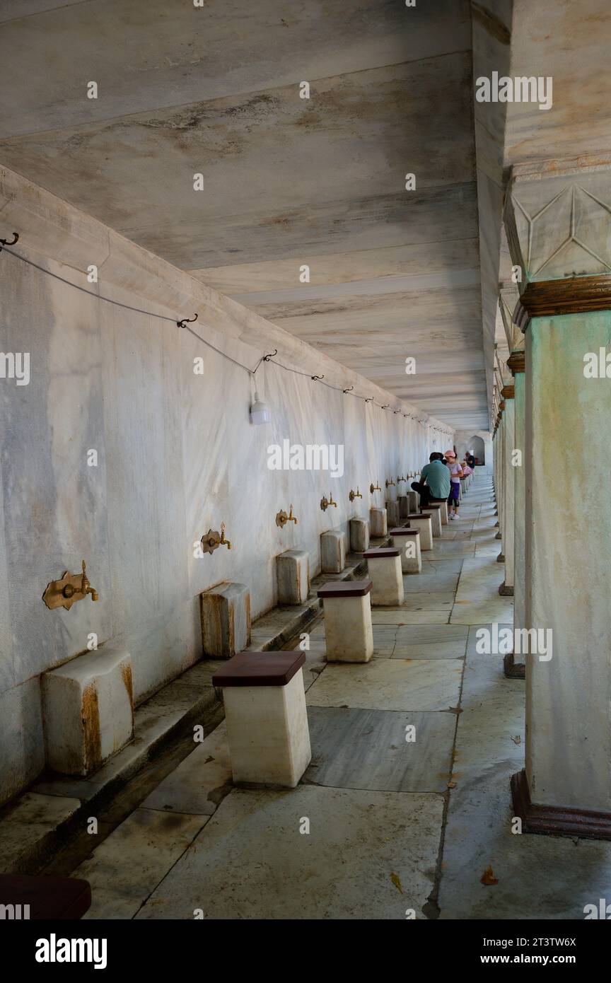 Les stations de nettoyage, presque vides, invitent les hommes musulmans à purifier leurs pieds avant d’entrer dans la vénérée mosquée bleue pour leur prière à Istambul. Banque D'Images