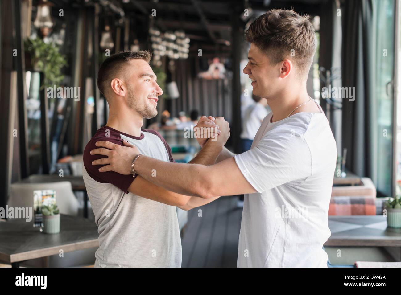 Deux heureux jeunes amis masculins serrant la main restaurant Banque D'Images