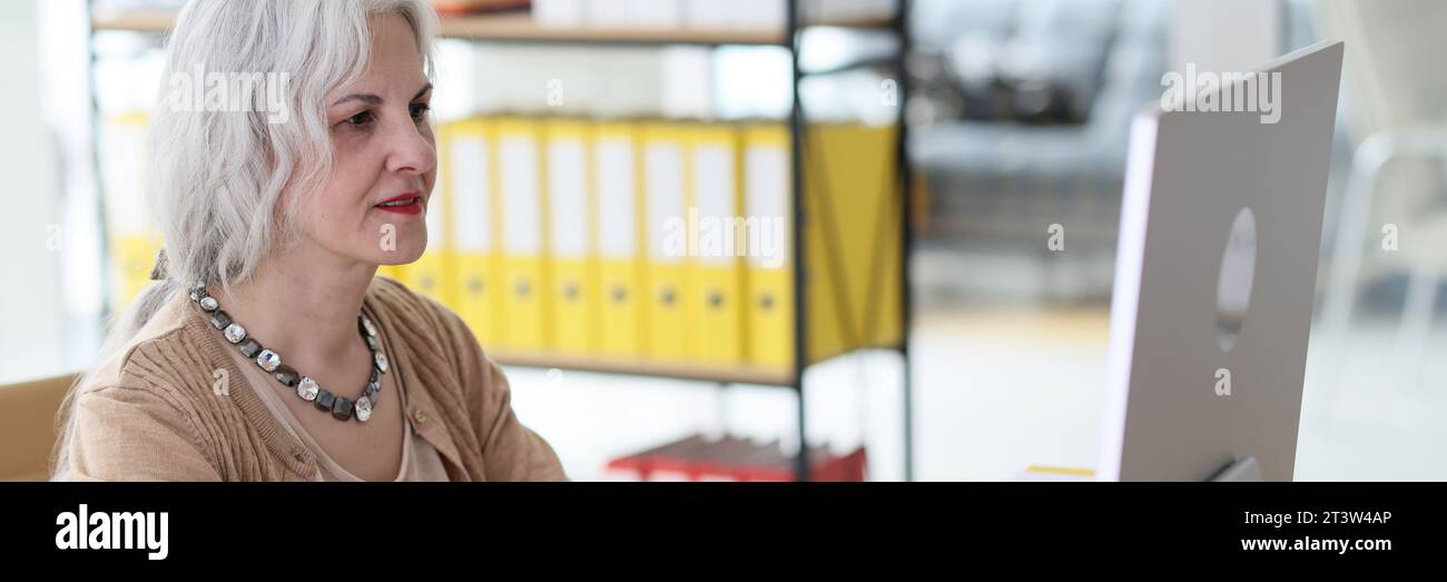 Un employé mature positif travaille sur un ordinateur au bureau Banque D'Images