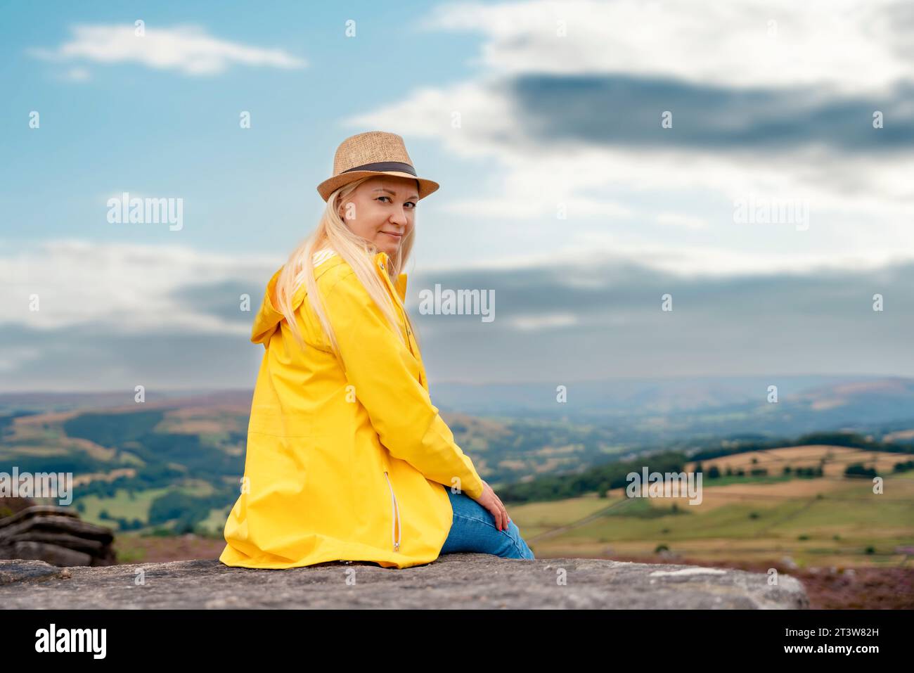 Une femme en manteau jaune atteignant la destination et assise sur des chaises de plage au sommet d'une colline ou d'une montagne au lever du soleil. Hiver froid britannique. Visite locale Banque D'Images