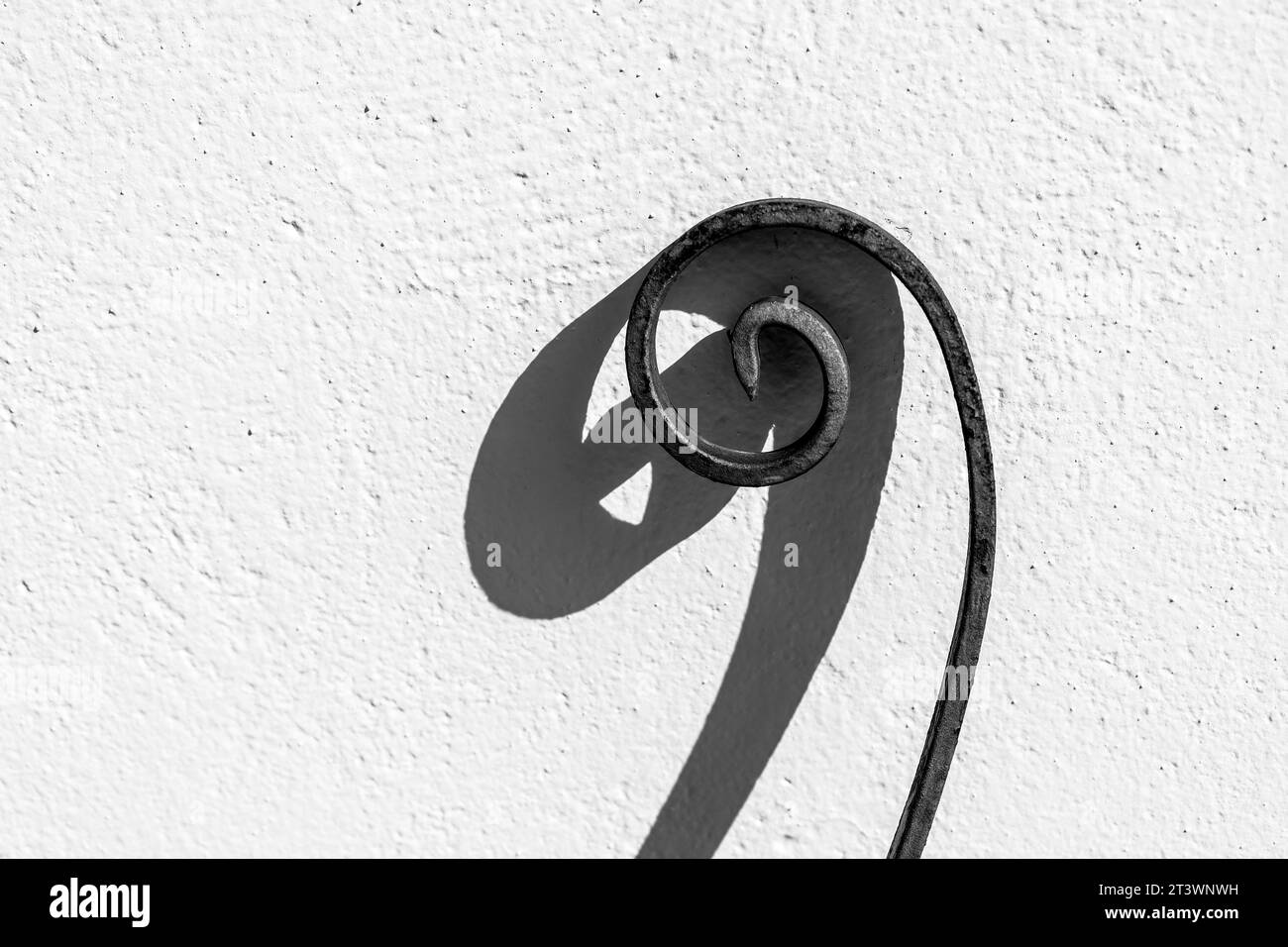 Spirale en fer forgé sur mur blanc. Photo monochrome Banque D'Images