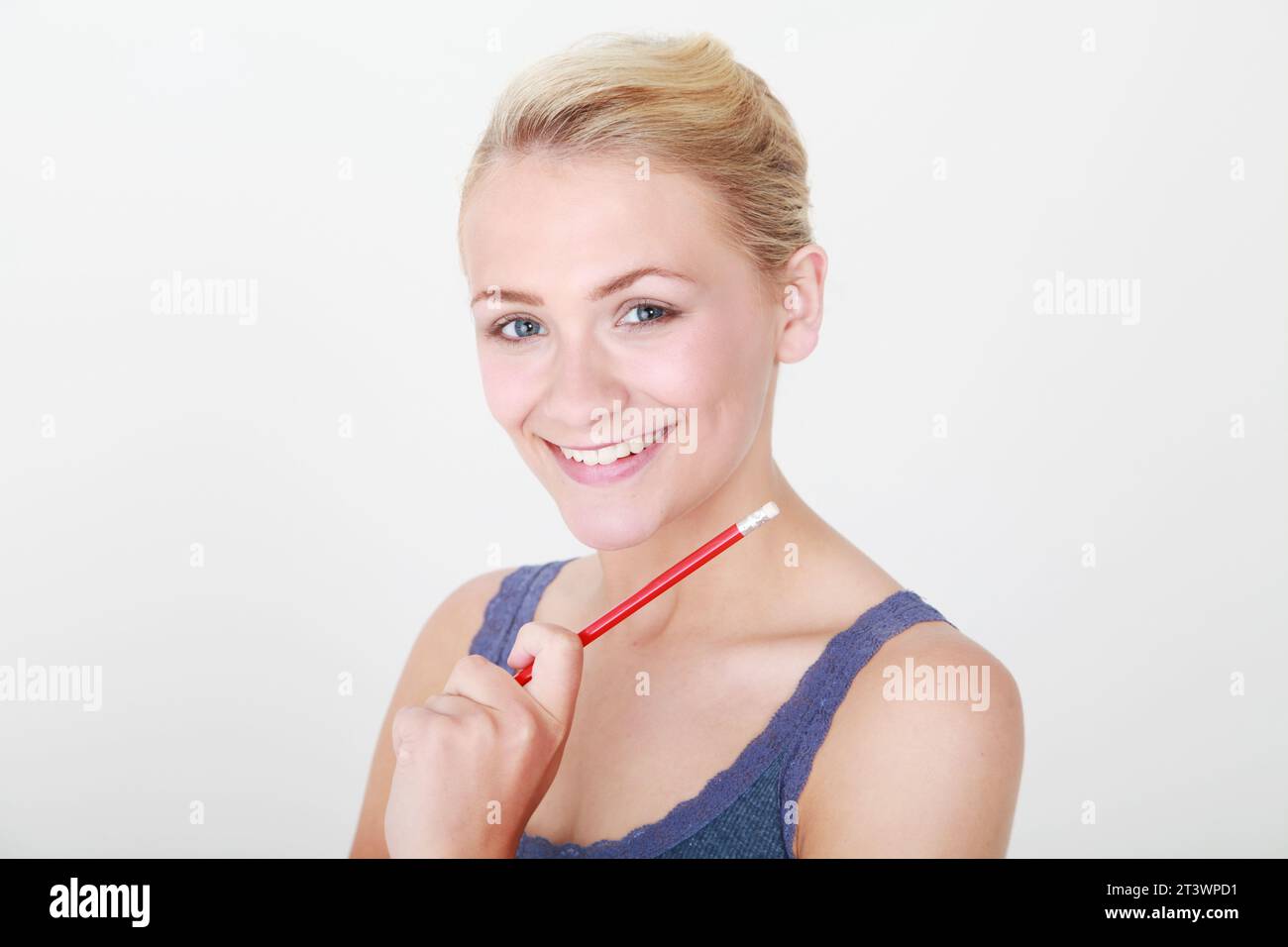 jeune modèle blonde tenant crayon rouge à visage sur fond blanc de studio Banque D'Images