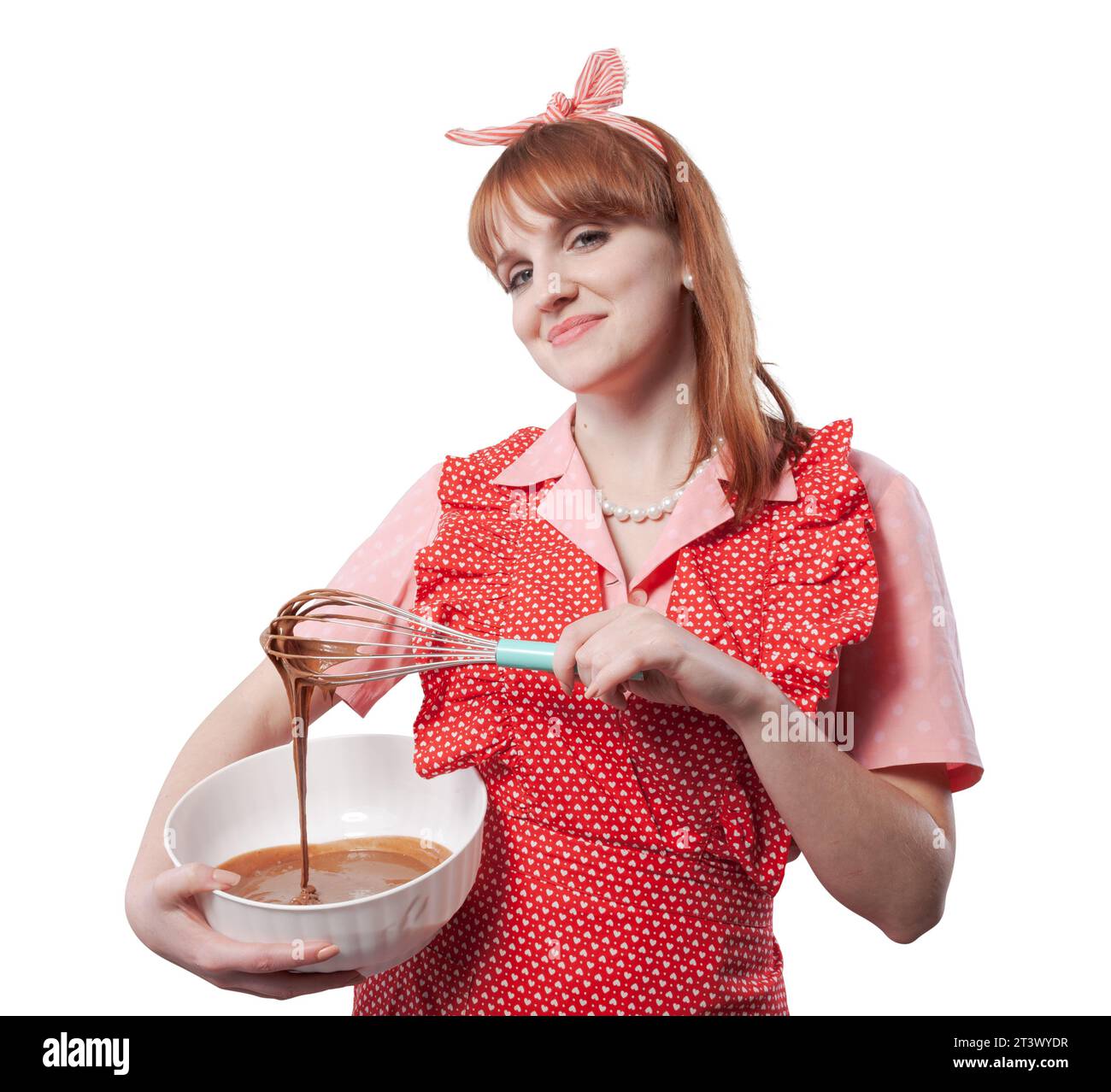 Femme au foyer de style rétro préparant un bonbon maison, elle remue la pâte dans un bol et regarde la caméra Banque D'Images