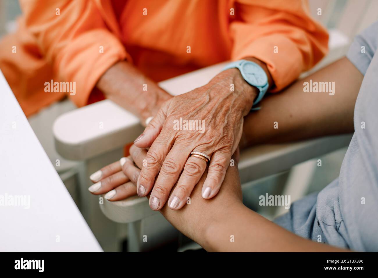 Section médiane d'une infirmière et d'une femme âgée se consolant en étant assise et tenant les mains Banque D'Images