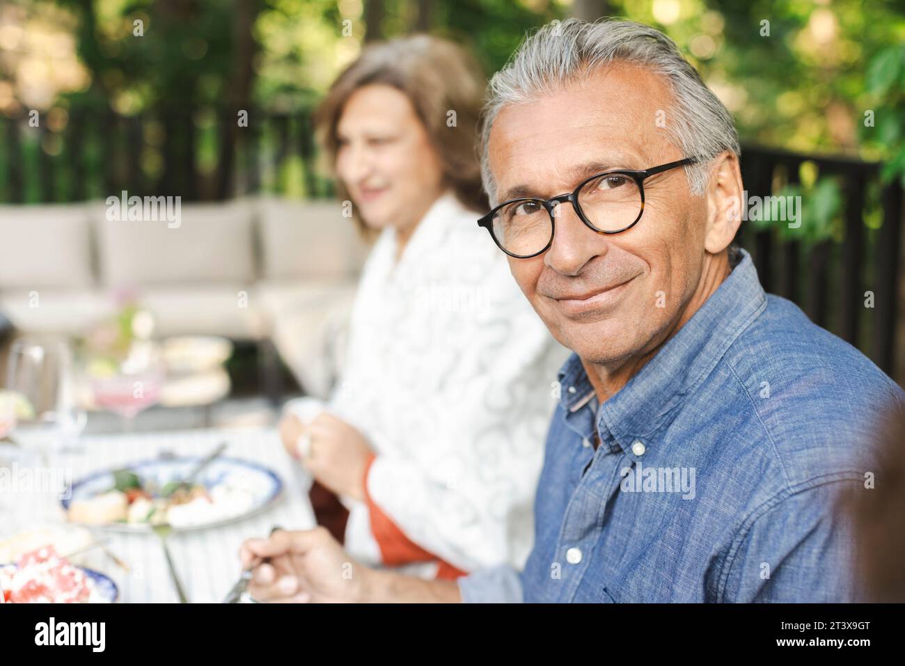 Portrait d'un homme âgé à la retraite souriant assis à la table à manger Banque D'Images