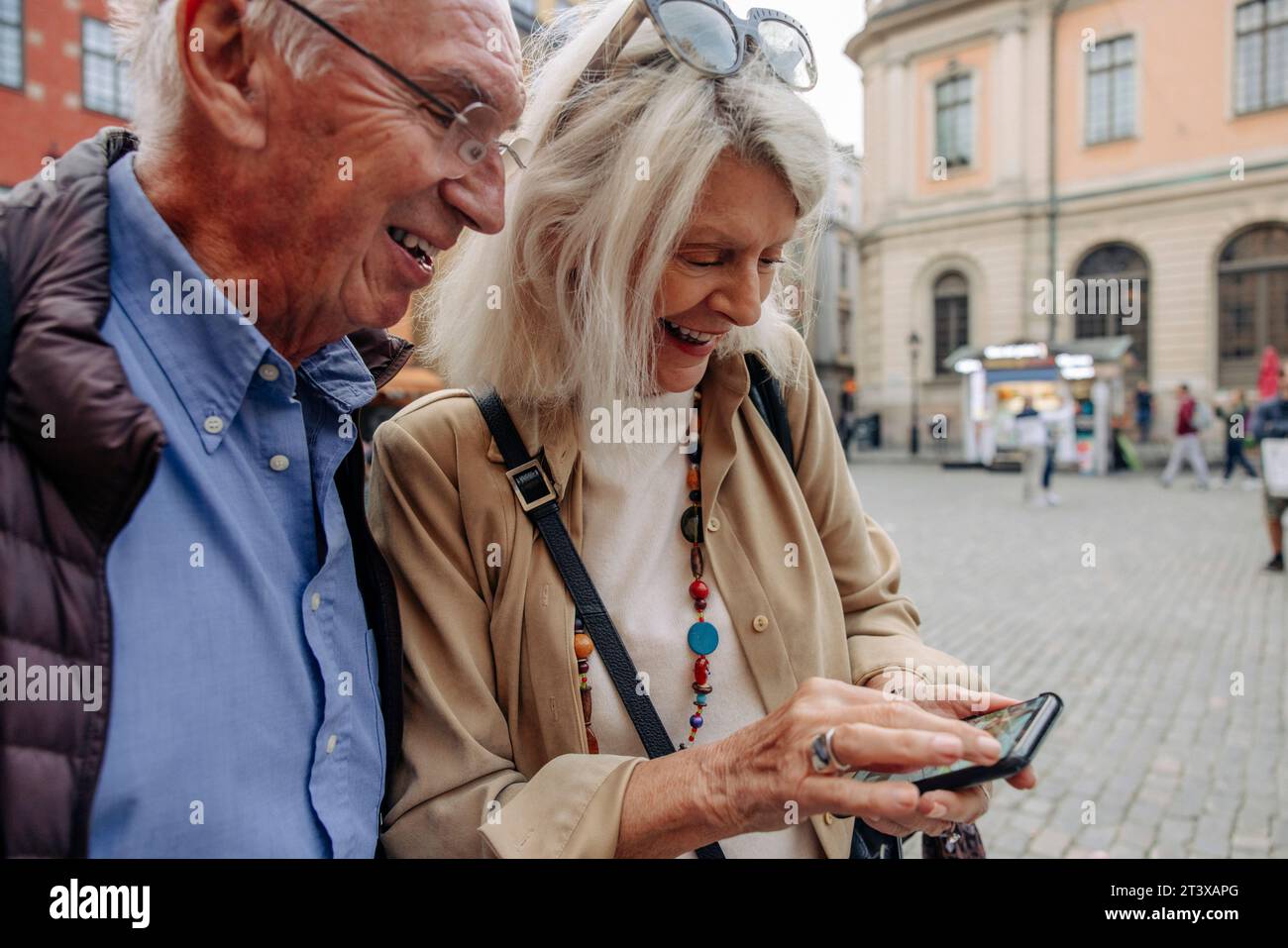 Heureux couple senior partageant téléphone intelligent tout en explorant la ville Banque D'Images