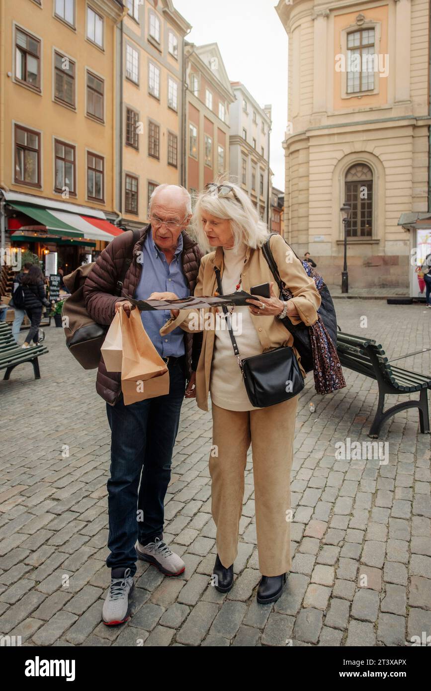 Pleine longueur de couple touristique senior lisant la carte ensemble dans la ville Banque D'Images