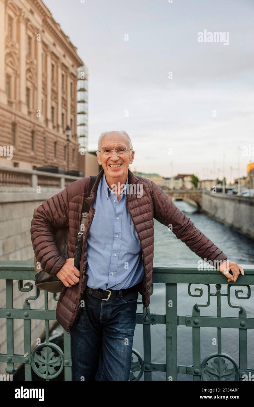 Portrait d'un homme âgé souriant appuyé sur la rampe au-dessus du canal Banque D'Images