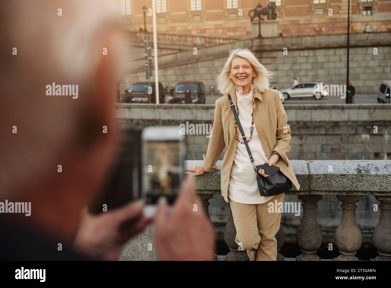 Homme senior photographiant une femme heureuse appuyée sur la rampe Banque D'Images