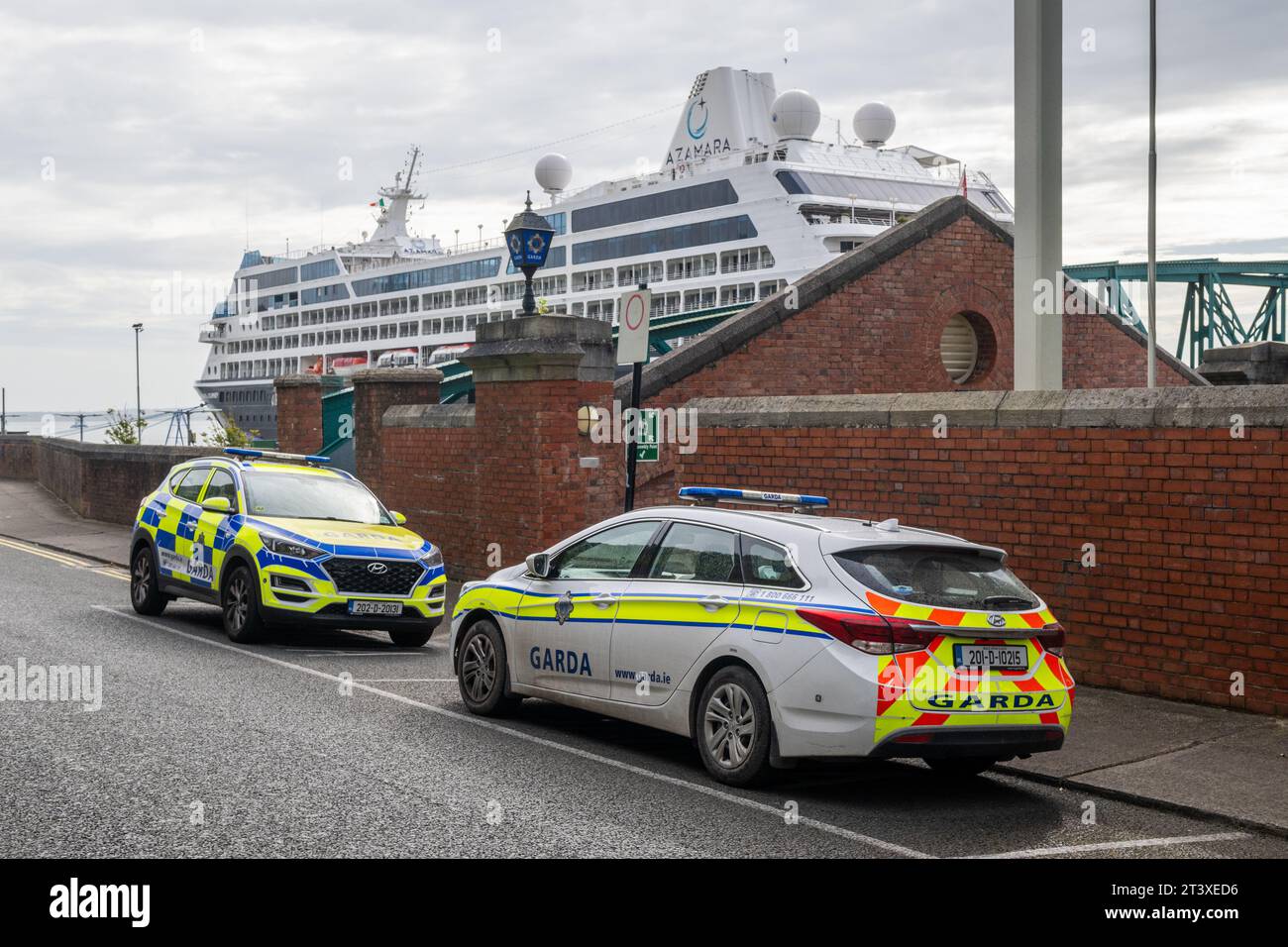 Voitures Garda garées à l'extérieur de Cobh Garda Station, Irlande, avec le paquebot de croisière 'Azamara Journey' amarré au terminal de croisière de Cobh en arrière-plan. Banque D'Images