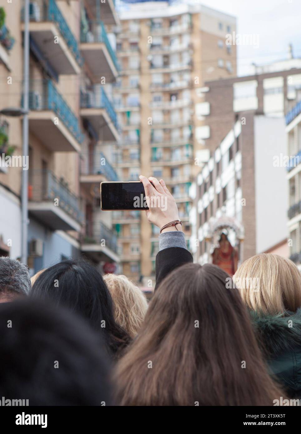Merida, Espagne - 10 décembre 2022 : une femme lève le bras pour enregistrer avec son smartphone la procession Eulalia de Mérida. Martyr vénéré avec grand dev Banque D'Images