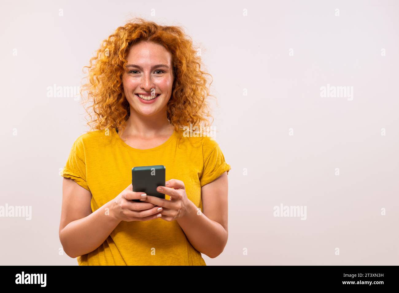 Image de femme heureuse de gingembre utilisant le téléphone Banque D'Images
