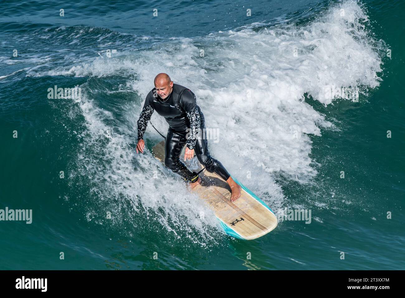 Un surfeur mature chevauchant une vague à Great Western à Newquay en Cornouailles au Royaume-Uni. Banque D'Images