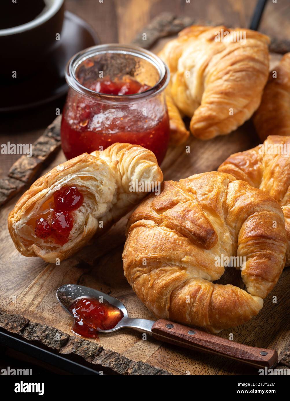 Croissants avec conserves de fraises et tasse de café sur plateau en bois rustici Banque D'Images