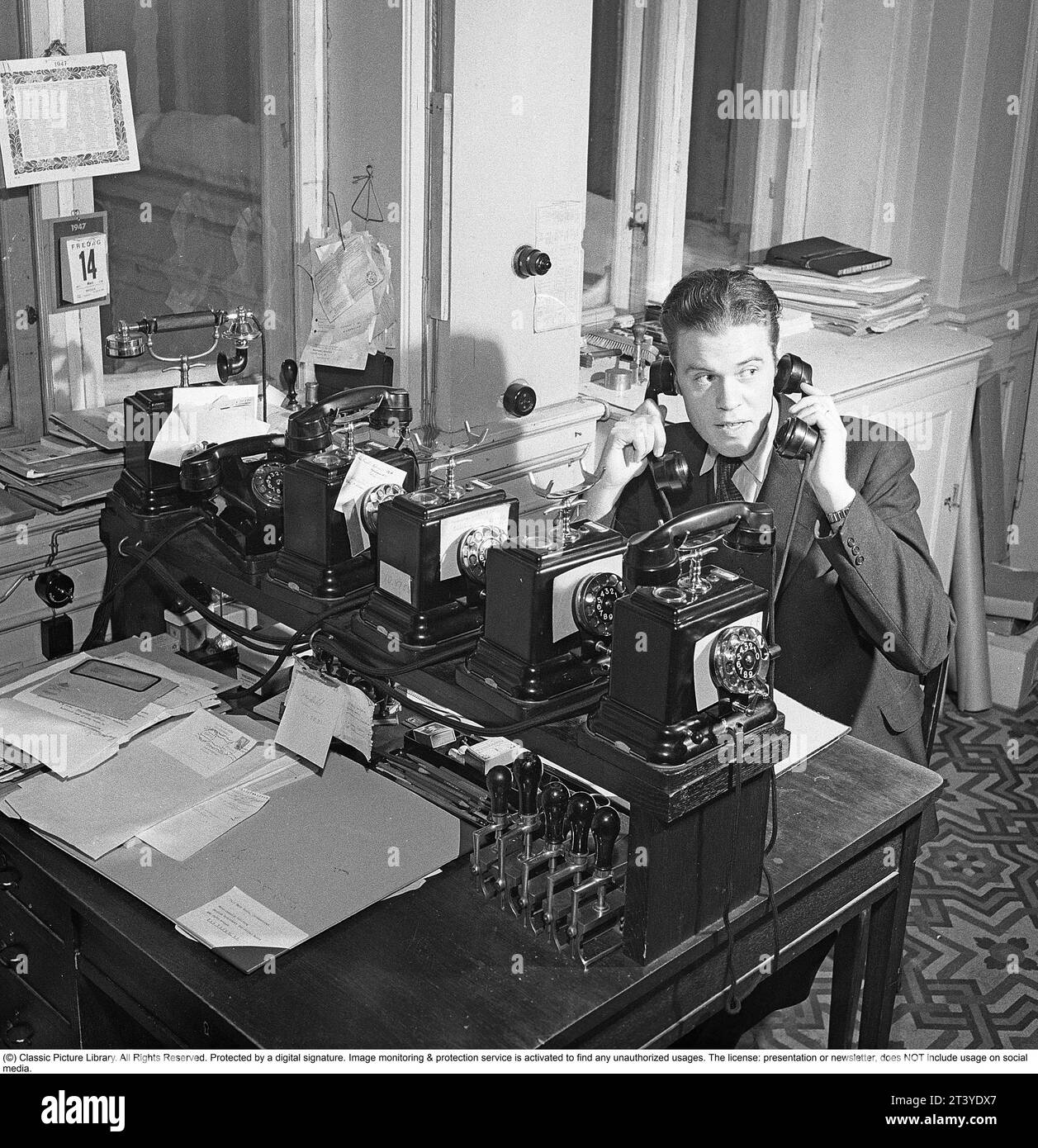 Dans les années 1940 Un homme dans un bureau semble occupé, parlant dans deux téléphones en même temps. Suède 1947. Kristoffersson réf AA37-11 Banque D'Images