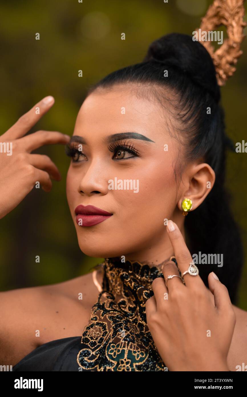 Belle femme asiatique avec maquillage et cheveux noirs attachés portant un morceau de bijoux noirs avant de danser sur la scène à l'intérieur de la fête de la jungle Banque D'Images