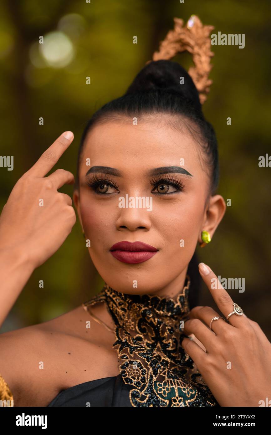 Belle femme asiatique avec maquillage et cheveux noirs attachés portant un morceau de bijoux noirs avant de danser sur la scène à l'intérieur de la fête de la jungle Banque D'Images