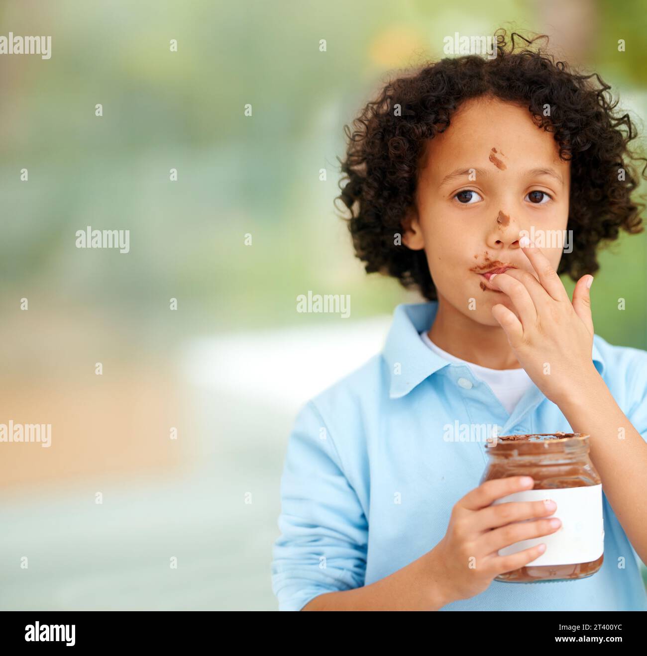 Mignon, portrait et enfant avec de la pâte à tartiner au chocolat à la maison avec une délicieuse collation sucrée ou une friandise. Sourire, heureux et visage de jeune garçon enfant du Mexique Banque D'Images