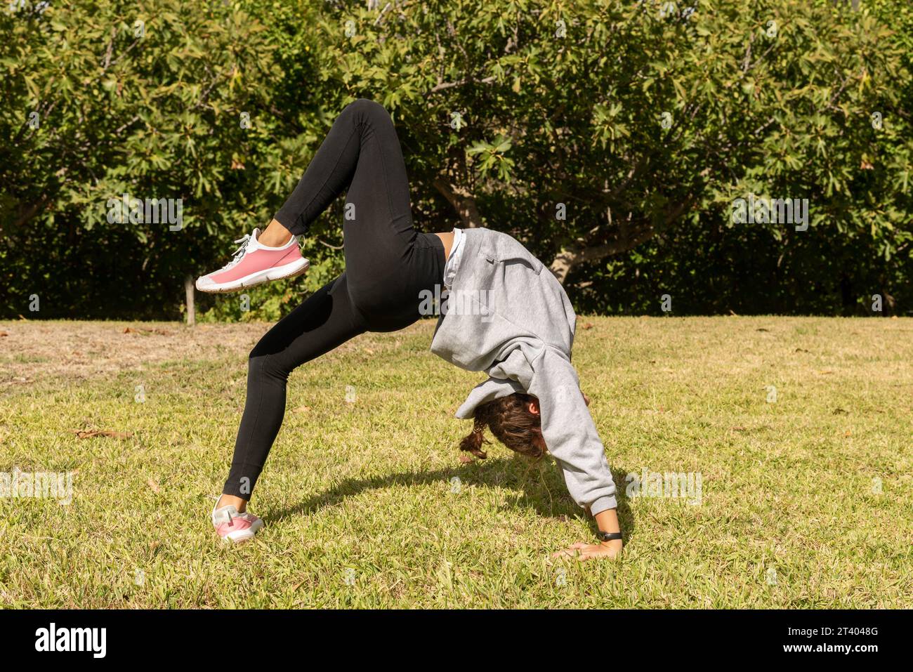 Une fille dans le parc faisant des exercices acrobatiques, jouant à l'extérieur et s'engageant dans des activités de gymnastique. Style de vie sain et sportif Banque D'Images
