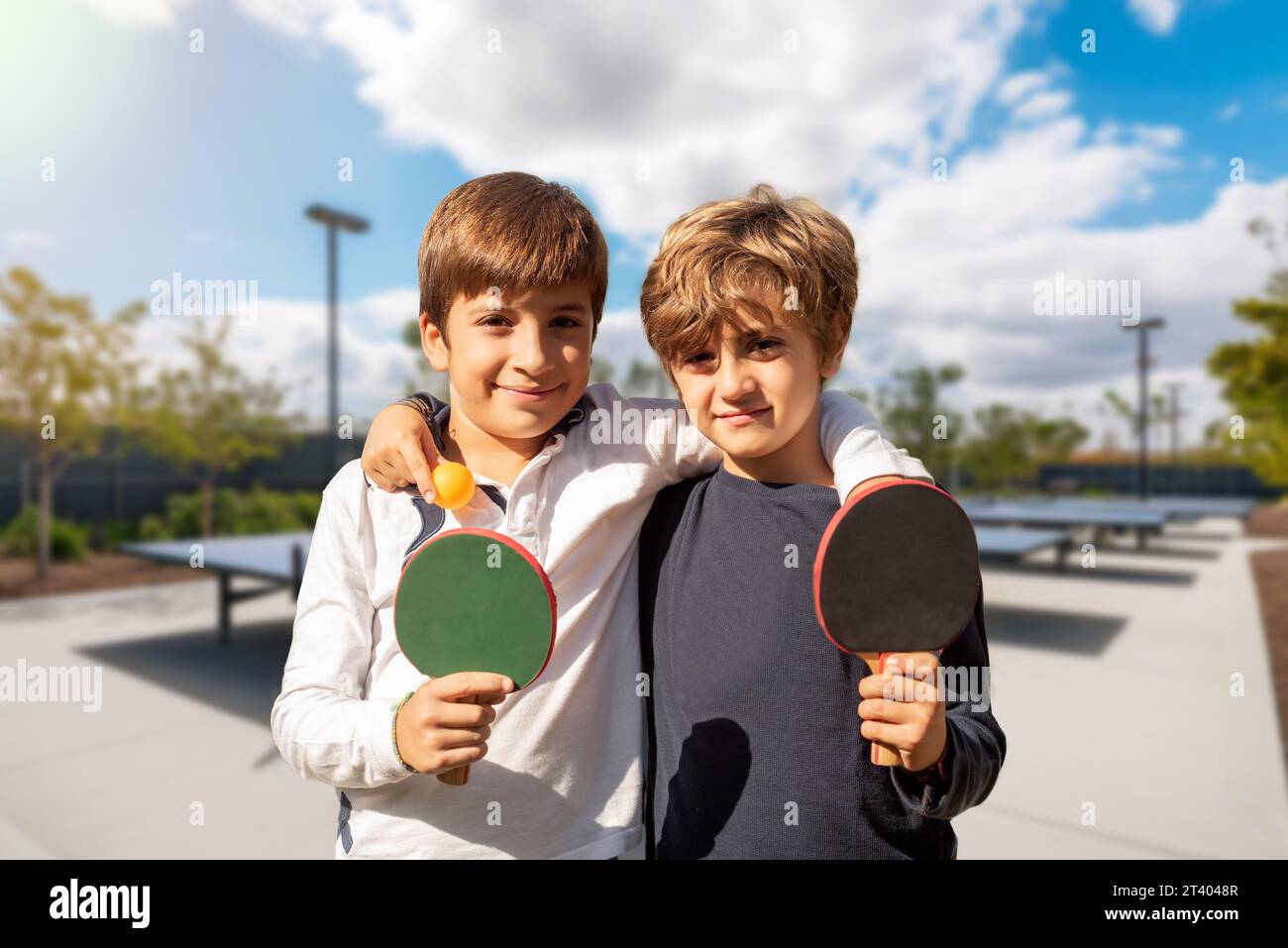 Deux enfants avec des pagaies de ping-pong jouant dans des installations sportives extérieures. L'esprit sportif de la jeunesse. Activités extrascolaires pour les enfants Banque D'Images