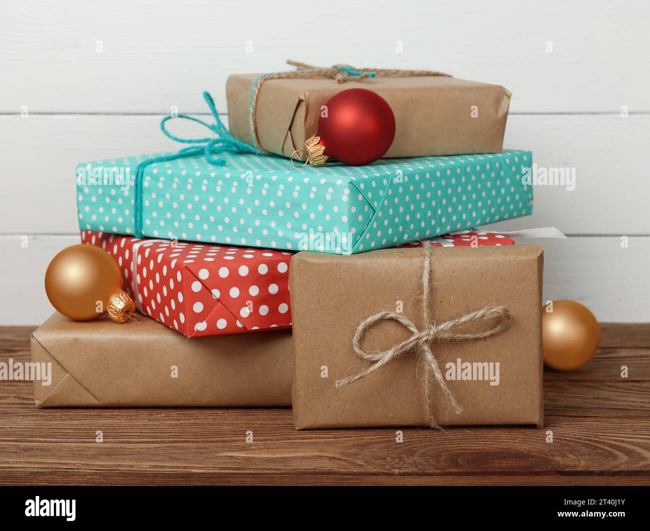 Gros plan de plusieurs cadeaux de Noël en papier rouge et marron sur une table en bois sur un mur blanc Banque D'Images