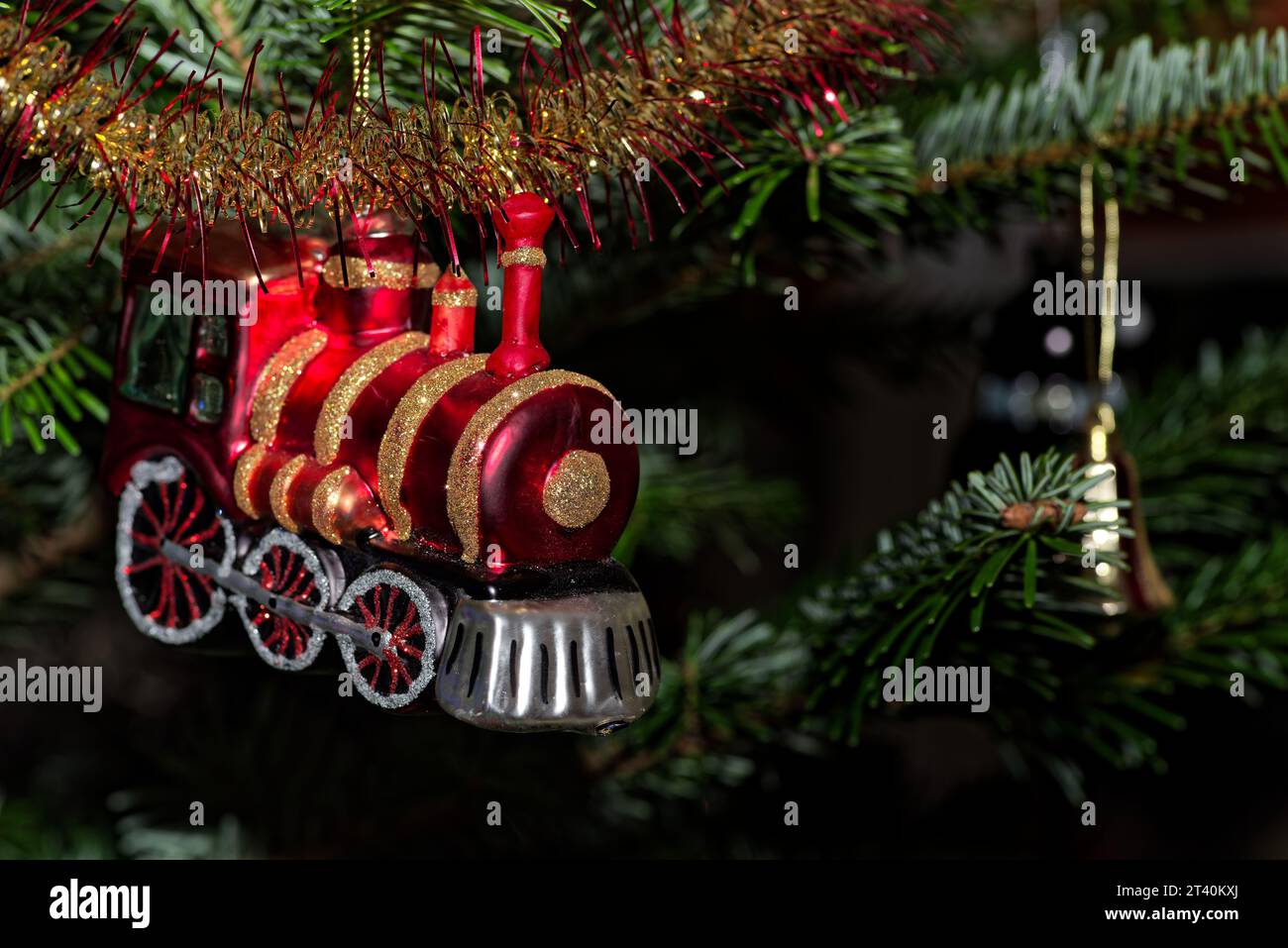 Gros plan du train rouge accroché à l'arbre Cristmas contre les branches vertes Banque D'Images