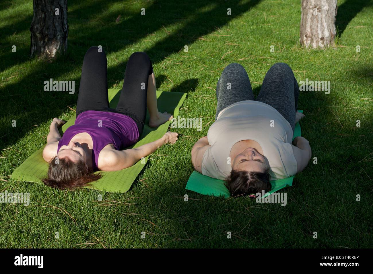 Deux femmes d'âge moyen pratiquent le yoga dans le parc de la ville, faisant des exercices allongés sur un tapis de fitness. Mode de vie sain, fitness, Pilates, perte de poids. surpoids avec Banque D'Images