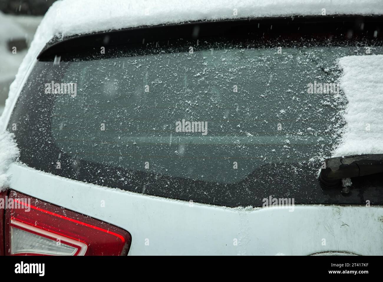 le verre de la voiture débarrassé d'une dérive de neige est à nouveau recouvert d'une couche de neige dans un blizzard hivernal, un gros plan de la vue arrière du véhicule. Banque D'Images