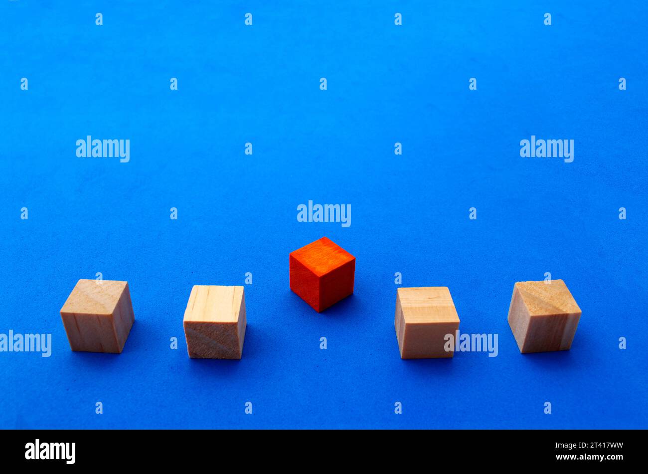 Cube en bois qui se différencie par sa couleur et sa position du reste des cubes alignés Banque D'Images