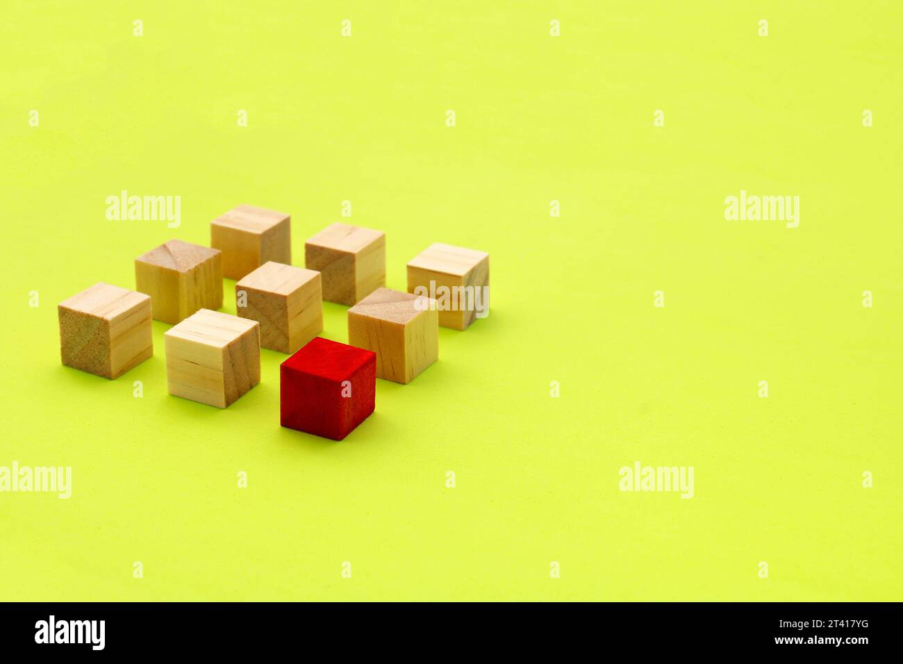 Cube en bois rouge devant un groupe de cubes alignés Banque D'Images