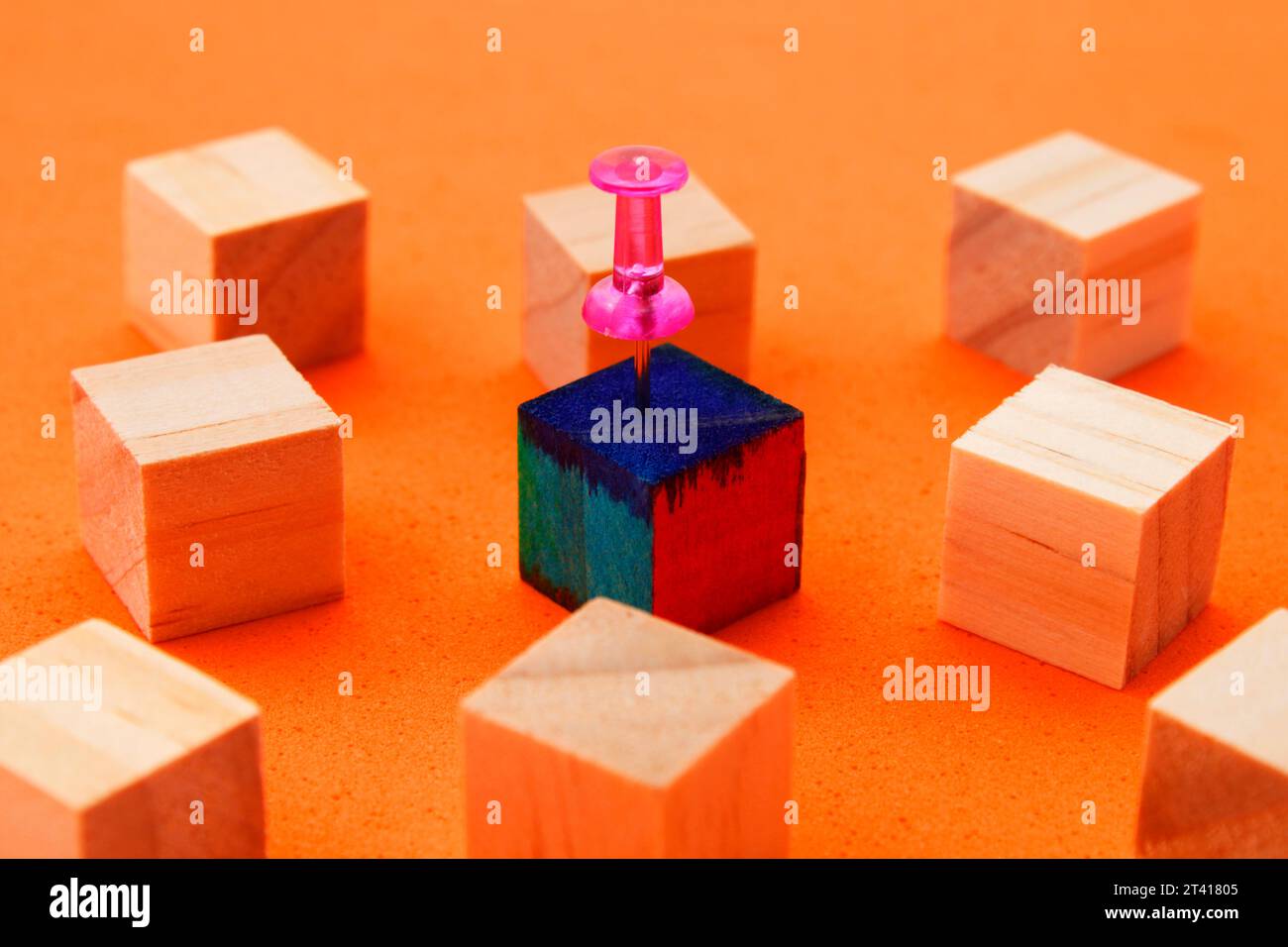 Groupe de cubes en bois avec l'un d'entre eux différencié par sa couleur et sélectionné par un pouce Banque D'Images