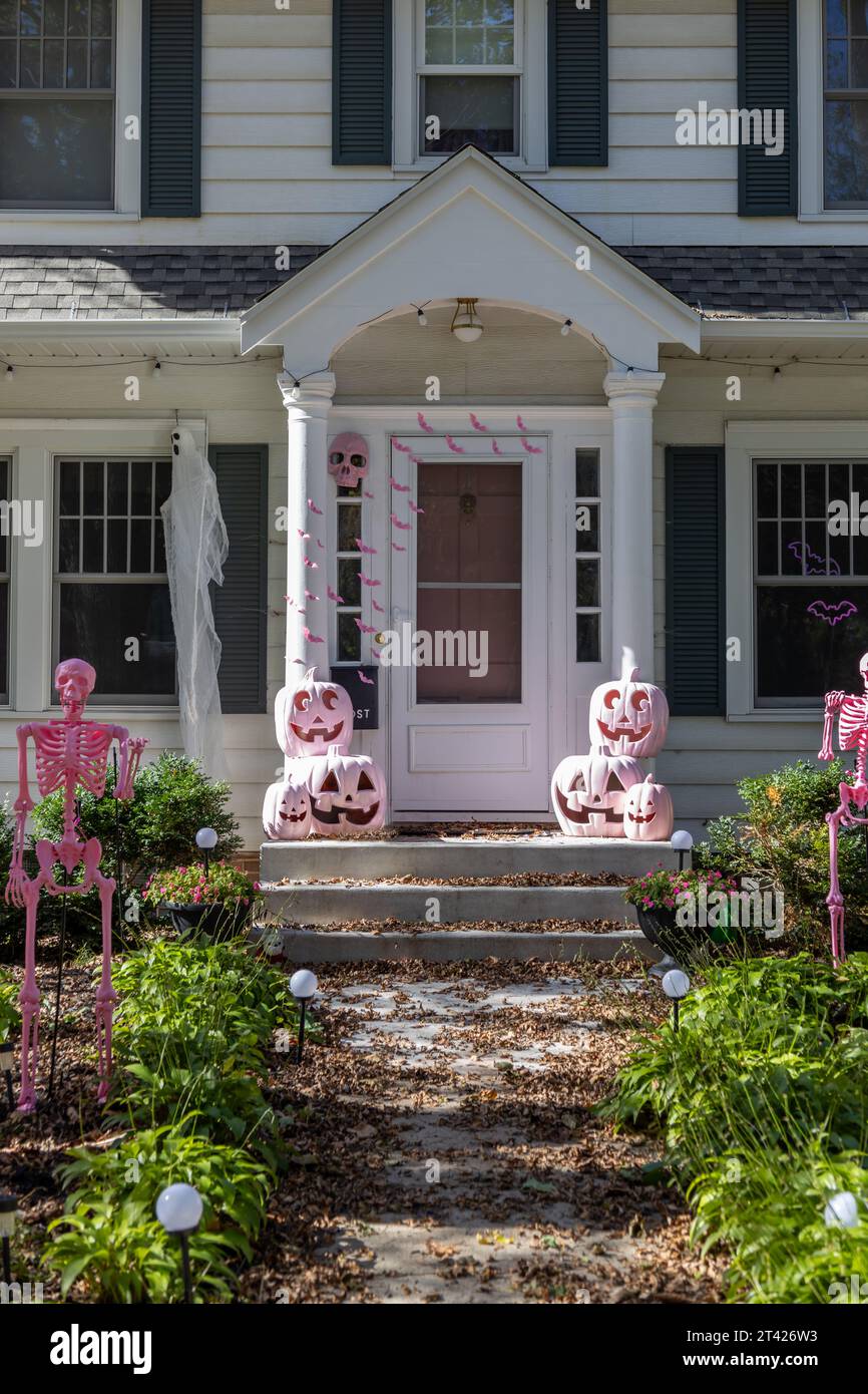 Vue rapprochée d'une porte d'entrée blanche sur une maison blanche de style traditionnel avec de jolies décorations d'Halloween, y compris des jack-o-lanternes roses Banque D'Images