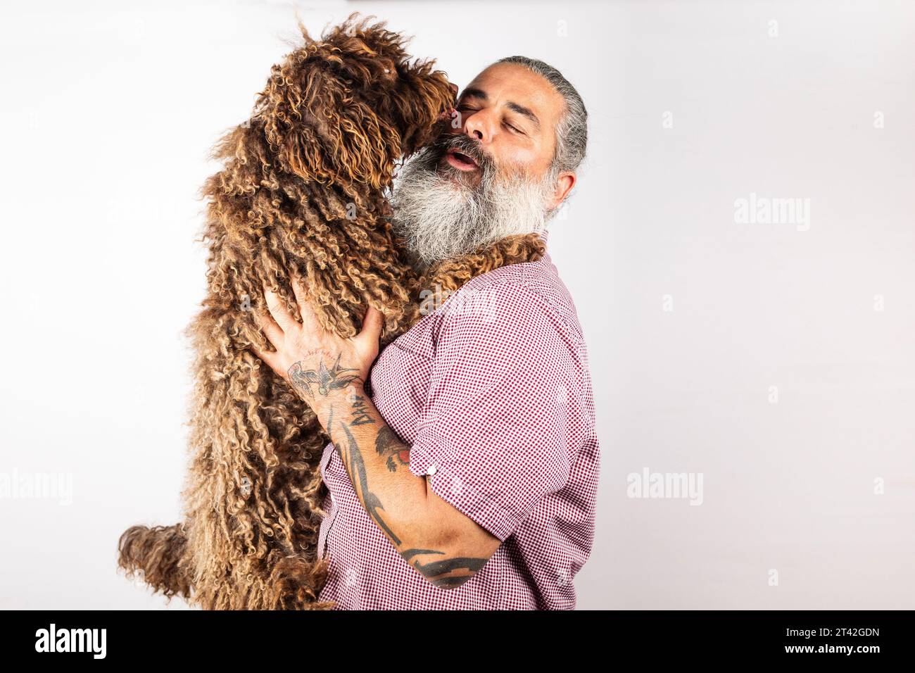 Heureux homme européen embrasse chien d'eau mignon, posant avec animal de compagnie Banque D'Images