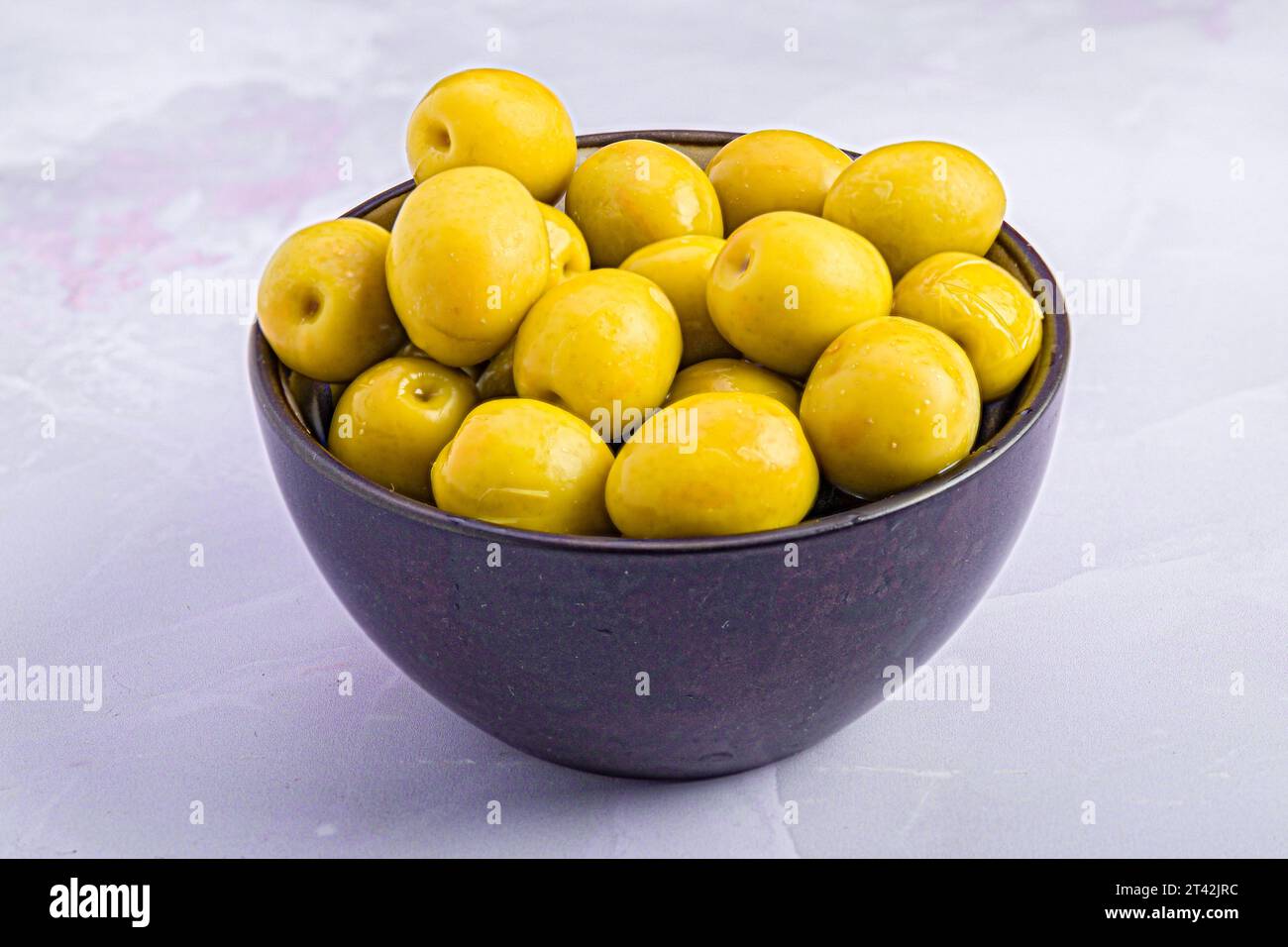 Une table blanche avec un bol rempli d'olives Manzanilla brillantes Banque D'Images