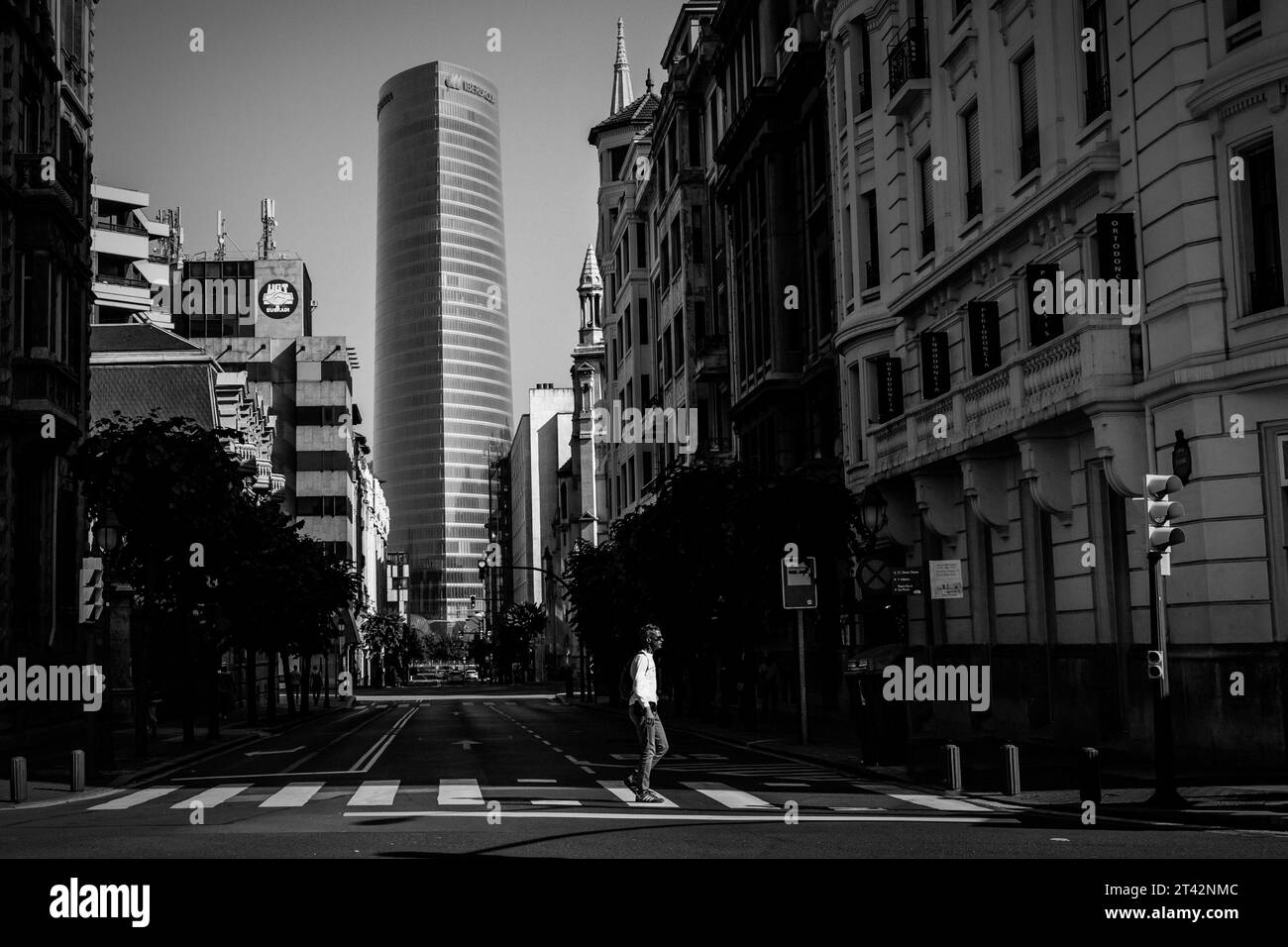 Une voiture vintage de style rétro roule sous la pluie dans une rue de la ville, avec des bâtiments, des lampadaires, et un trottoir humide visibles en arrière-plan Banque D'Images