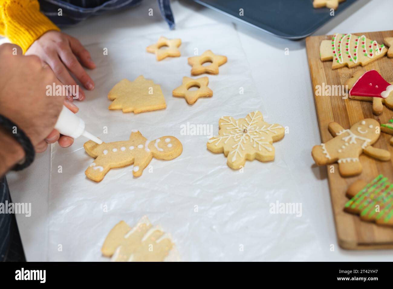 Section médiane du couple caucasien décorant des biscuits de noël dans la cuisine, espace de copie Banque D'Images