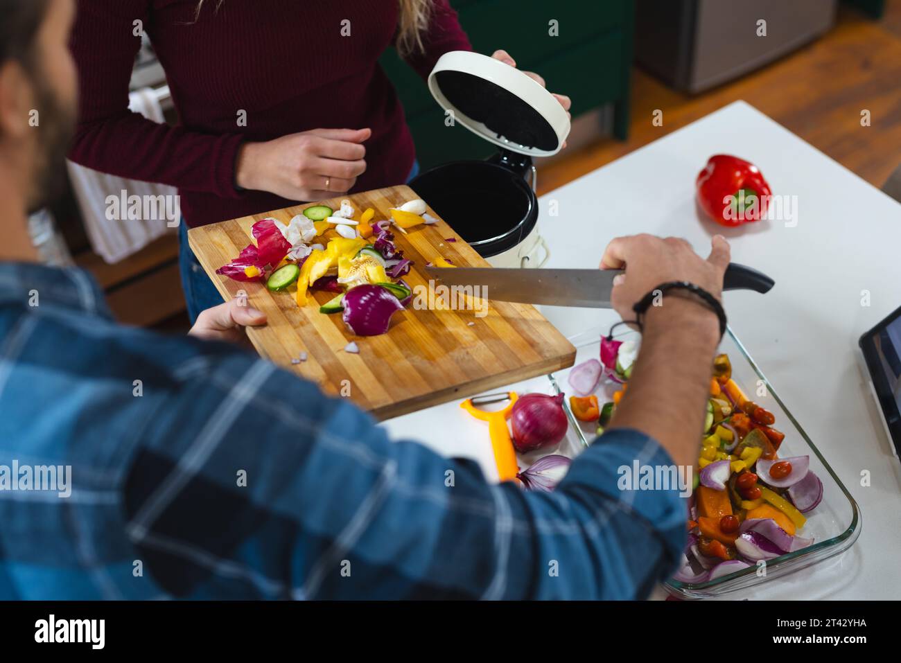 Section médiane du couple caucasien préparant la nourriture, compostant les déchets végétaux dans la cuisine Banque D'Images