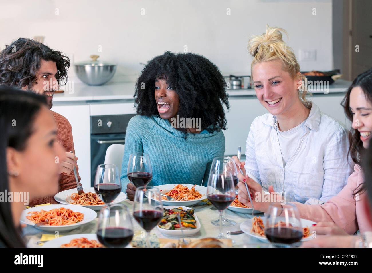 Heureux groupe d'amis mangeant des pâtes au dîner à la maison Banque D'Images