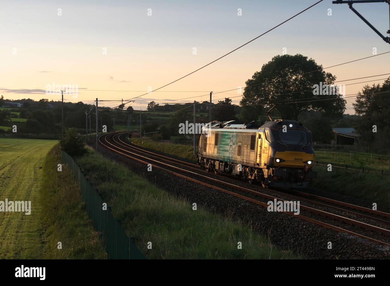 Direct Rail Services locomotive électrique de classe 88 attrapant le moteur léger doré couchant sur la ligne principale de la côte ouest à Cumbria Banque D'Images