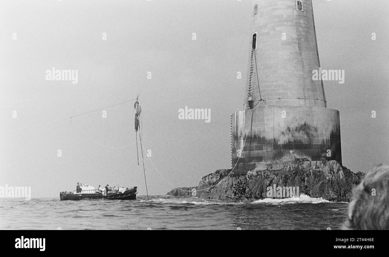 Un lancement de ravitaillement Trinity House se tenant au pied du rocher sur lequel se dresse le phare de Bishops Rock, à 4 miles au large des îles Scilly. Livrer Banque D'Images